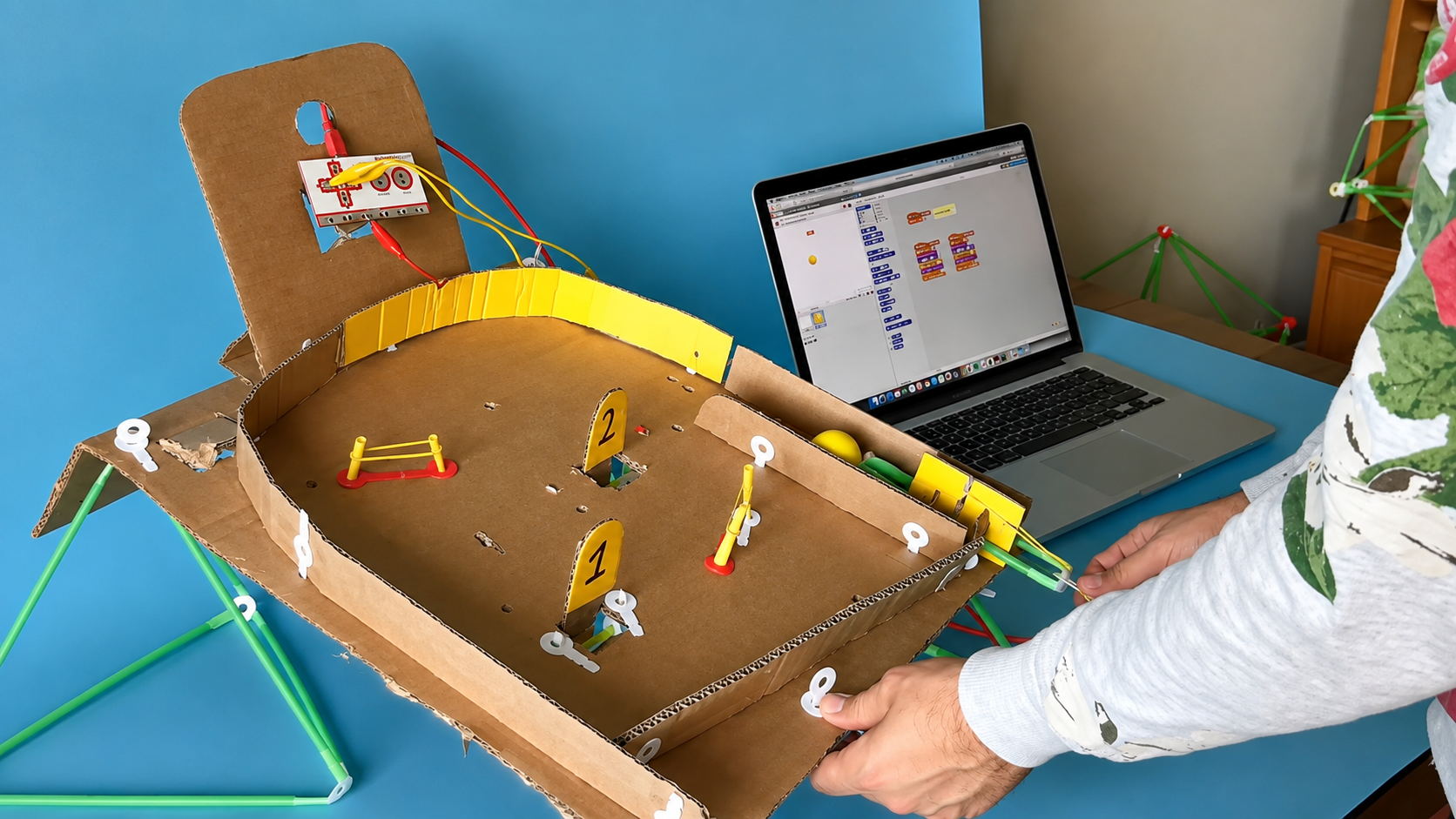 A cardboard pinball machine built with plastic straw connectors, wired to a Makey Makey and a laptop running Scratch