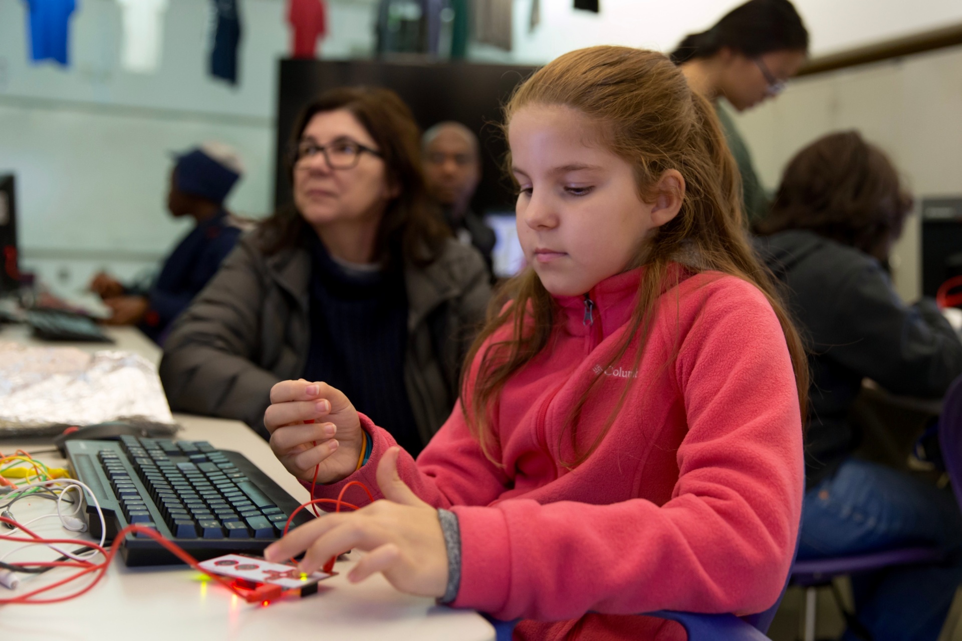 A student smiling while building an invention with a Makey Makey kit