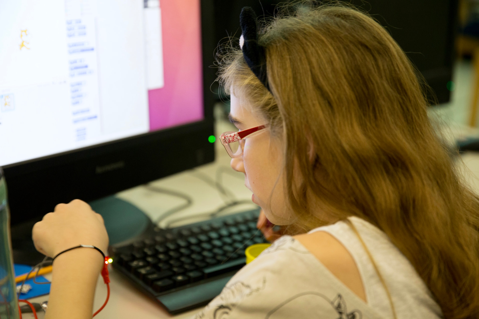 Girl coding in Scratch with a Makey Makey wristband