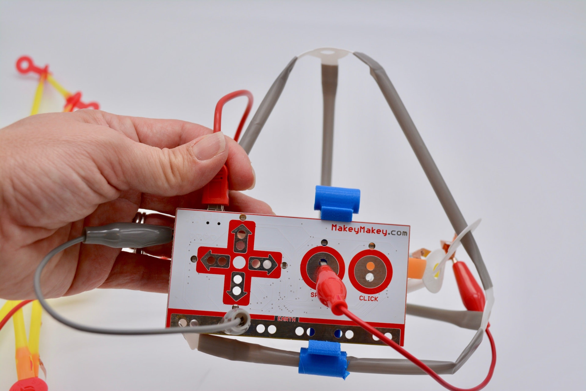 A hand holding a Makey Makey wired into a hand-built prototype