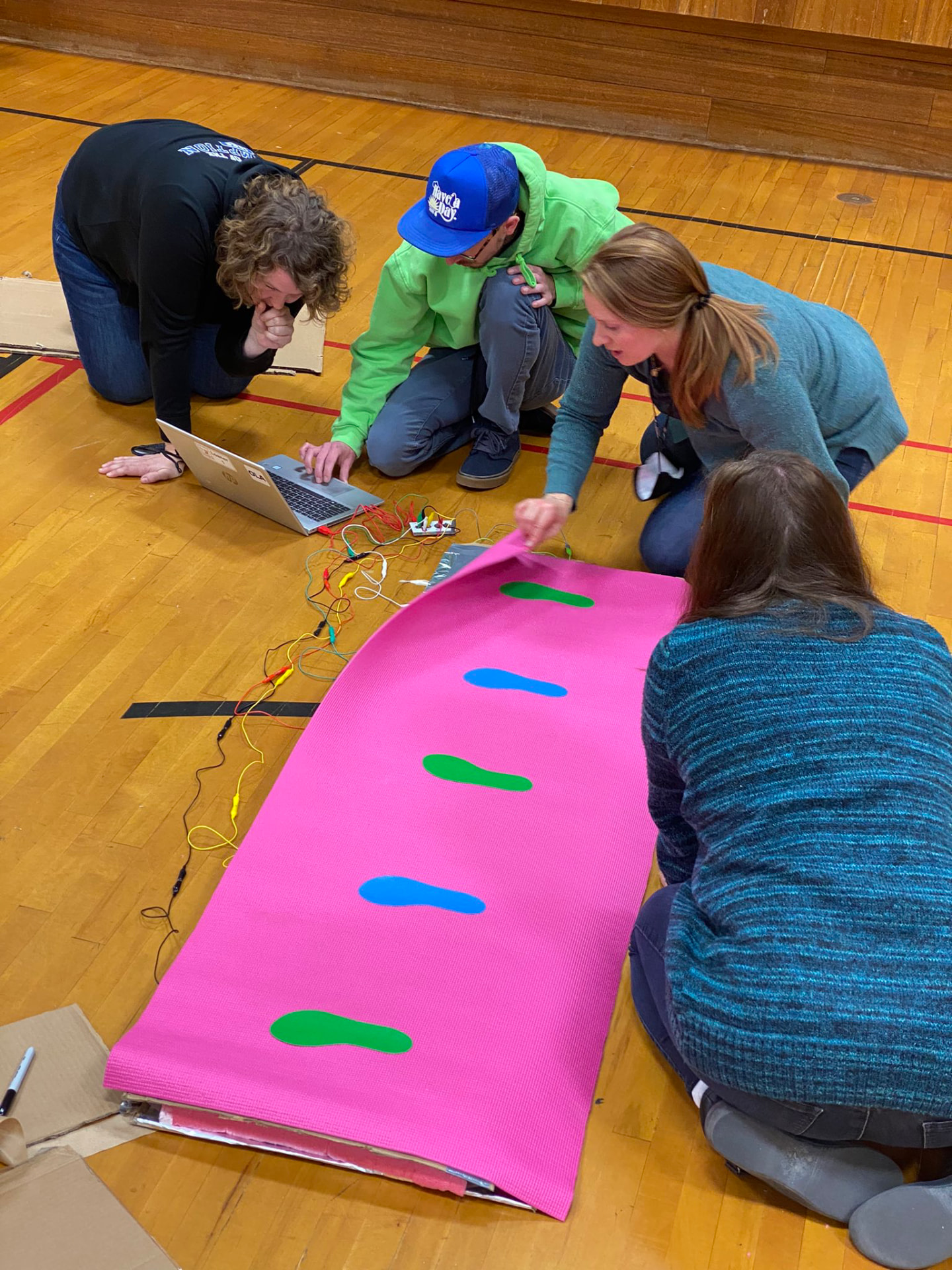 Teacher standing on a large foil-and-tape floor mat wired to a Makey Makey